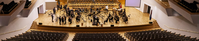 Veranstaltungen Orchester auf der Bühne eines Konzertsaals mit leeren Zuschauersitzen.