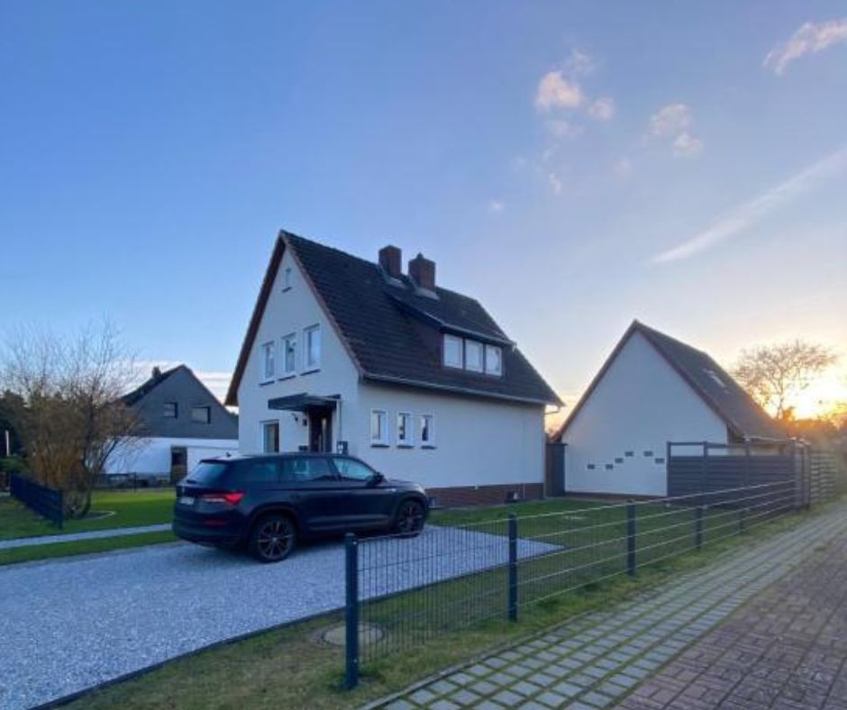 Hausansicht beim Sonnenaufgang mit Blick in den Vorgarten und Parkplatz